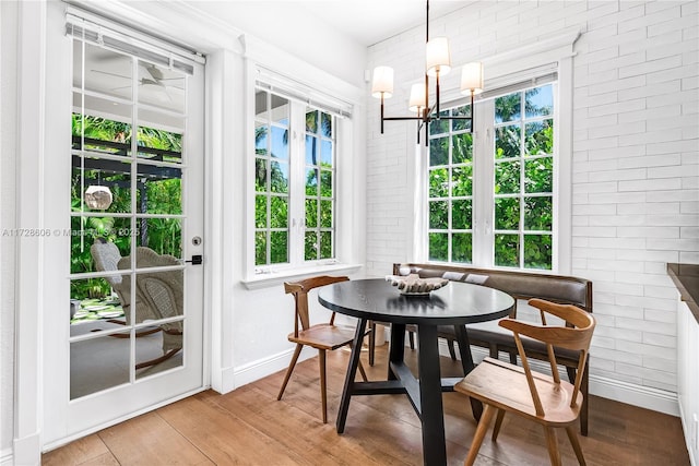 dining room featuring breakfast area, brick wall, wood-type flooring, and an inviting chandelier