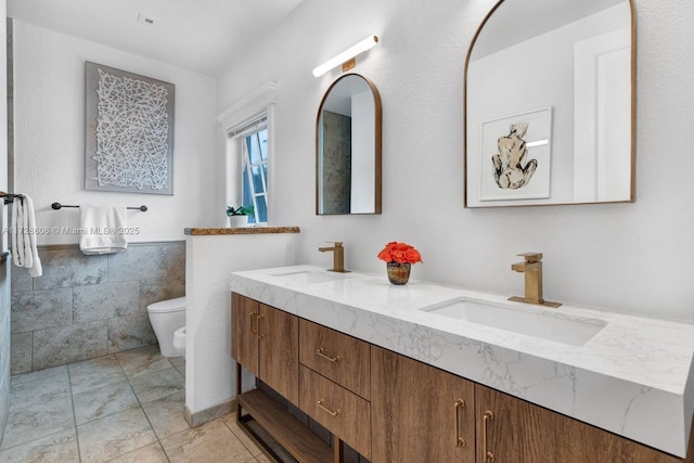 bathroom with vanity, toilet, and tile walls