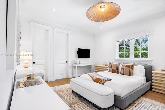 bedroom featuring ornamental molding and light hardwood / wood-style flooring