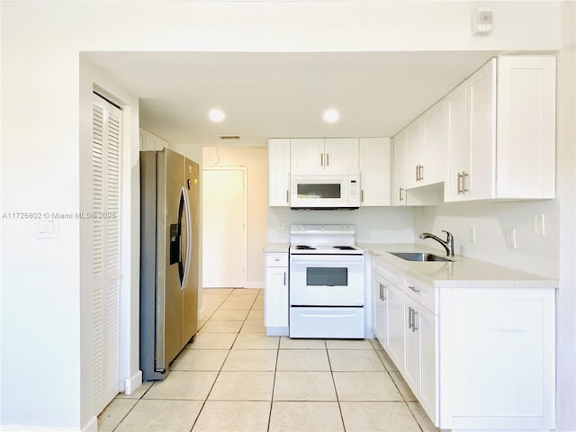 kitchen with light tile patterned flooring, sink, white cabinets, and white appliances