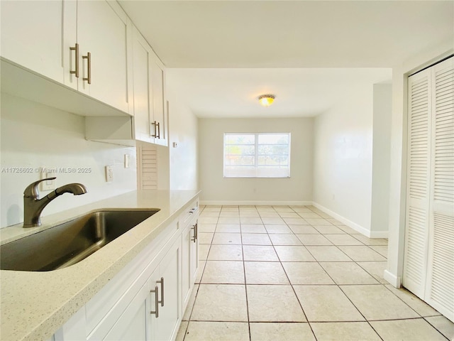 kitchen with white cabinets, light stone countertops, sink, and light tile patterned floors