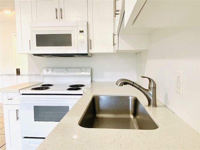 kitchen with light stone countertops, sink, white appliances, and white cabinetry