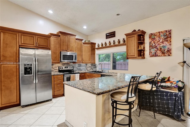 kitchen with sink, light tile patterned floors, stainless steel appliances, vaulted ceiling, and dark stone counters