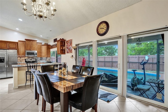 dining area featuring a notable chandelier, vaulted ceiling, a textured ceiling, and light tile patterned floors