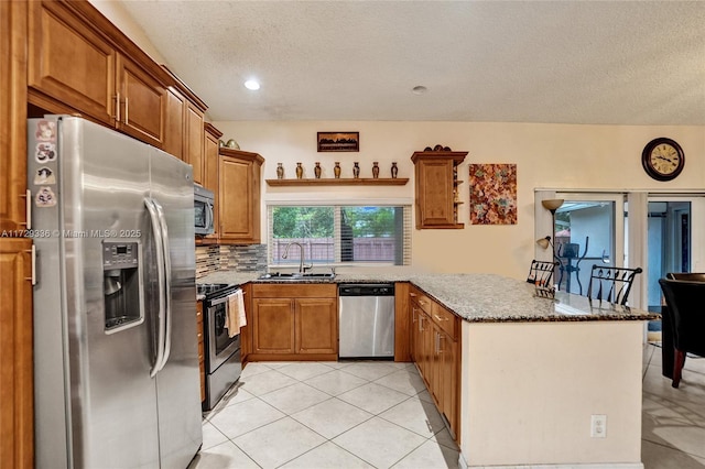 kitchen featuring decorative backsplash, dark stone counters, kitchen peninsula, stainless steel appliances, and a textured ceiling