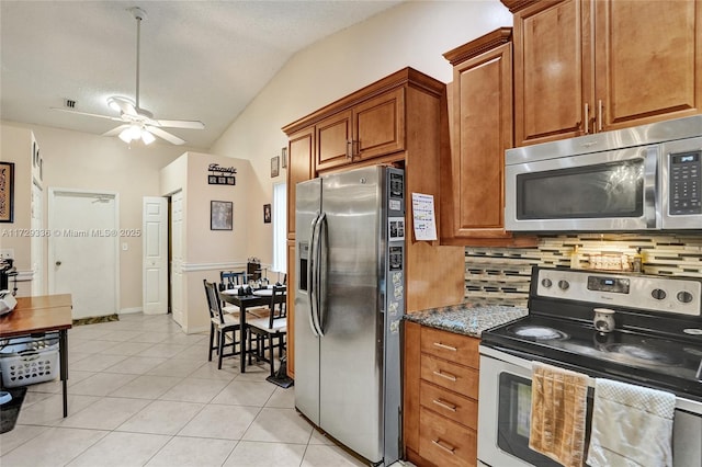 kitchen with vaulted ceiling, backsplash, light tile patterned floors, stainless steel appliances, and a textured ceiling