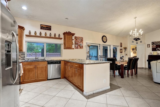 kitchen with sink, a textured ceiling, light tile patterned floors, appliances with stainless steel finishes, and kitchen peninsula