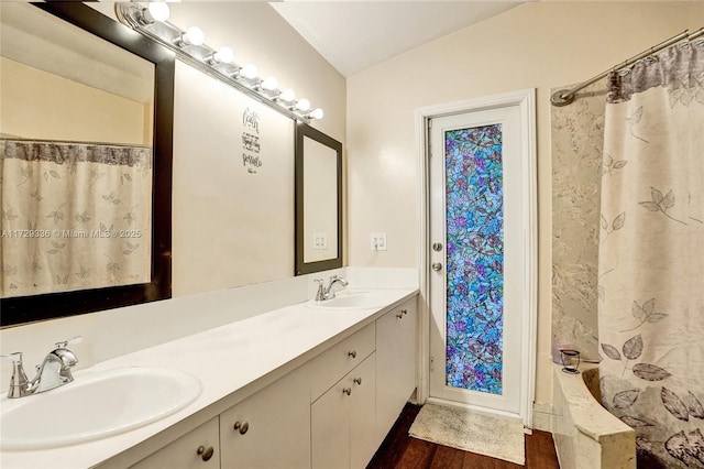 bathroom with lofted ceiling, shower / bathtub combination with curtain, hardwood / wood-style floors, and vanity