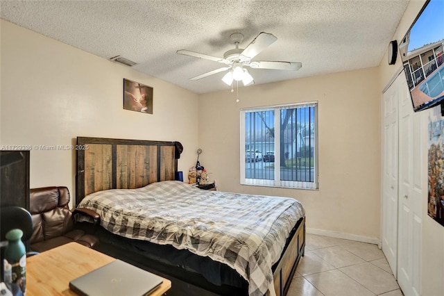 bedroom featuring light tile patterned floors, ceiling fan, multiple windows, a textured ceiling, and a closet