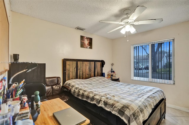 tiled bedroom with ceiling fan and a textured ceiling