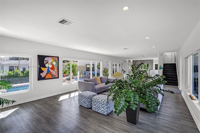 living area featuring dark wood-type flooring, stairway, visible vents, and a healthy amount of sunlight