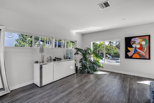interior space with baseboards, visible vents, and dark wood-style flooring