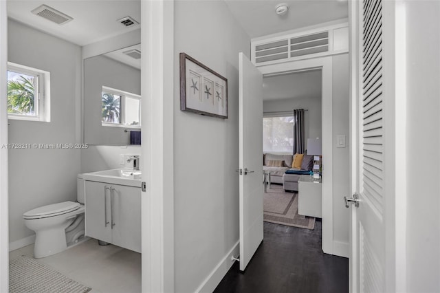 hallway featuring baseboards, visible vents, and a healthy amount of sunlight