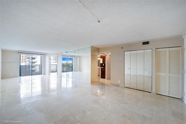 empty room with a textured ceiling and crown molding