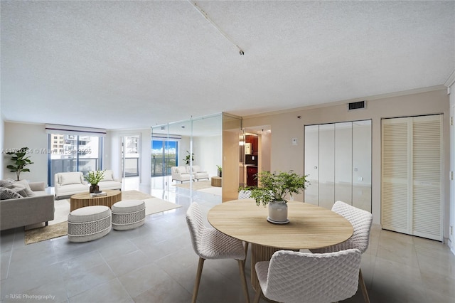 dining room with a textured ceiling and crown molding