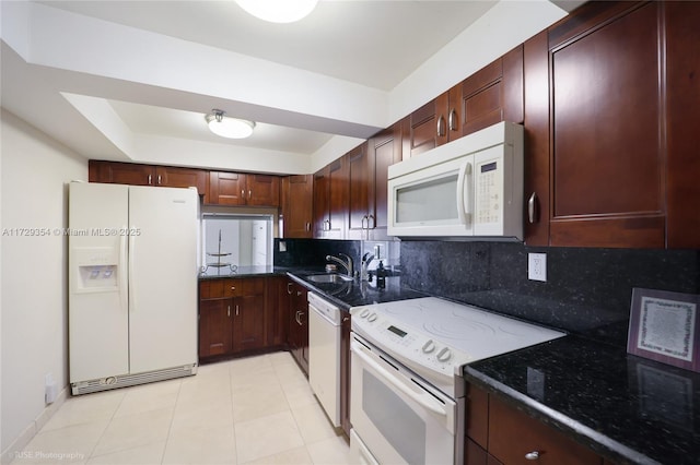 kitchen featuring light tile patterned flooring, backsplash, dark stone counters, and white appliances