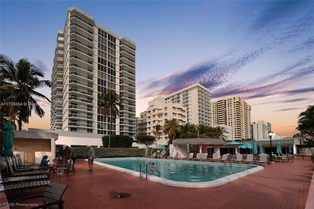 pool at dusk featuring a patio area