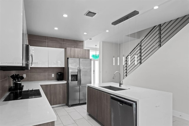 kitchen featuring white cabinetry, stainless steel appliances, backsplash, hanging light fixtures, and sink