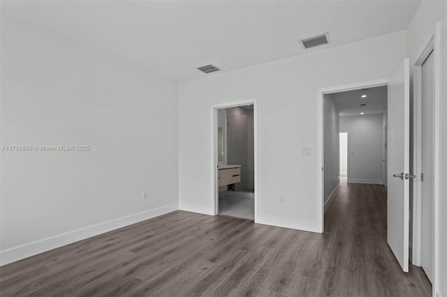 unfurnished bedroom featuring dark wood-type flooring and connected bathroom