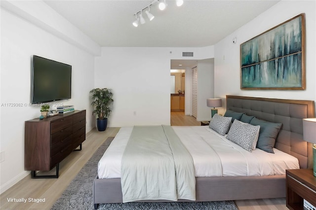 bedroom featuring ensuite bathroom and light hardwood / wood-style flooring