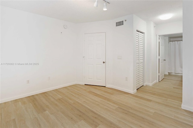 spare room with light wood-type flooring and a textured ceiling