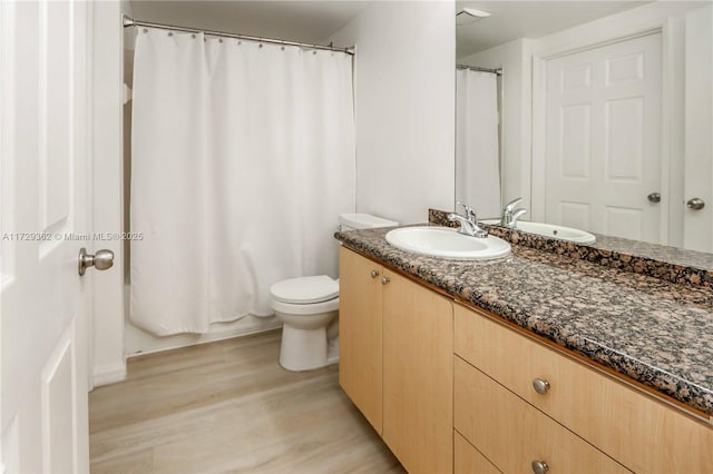 bathroom featuring toilet, vanity, and hardwood / wood-style floors