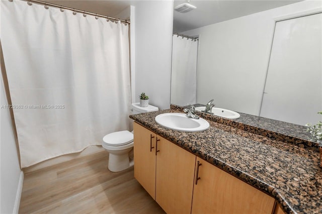 bathroom with toilet, hardwood / wood-style floors, and vanity