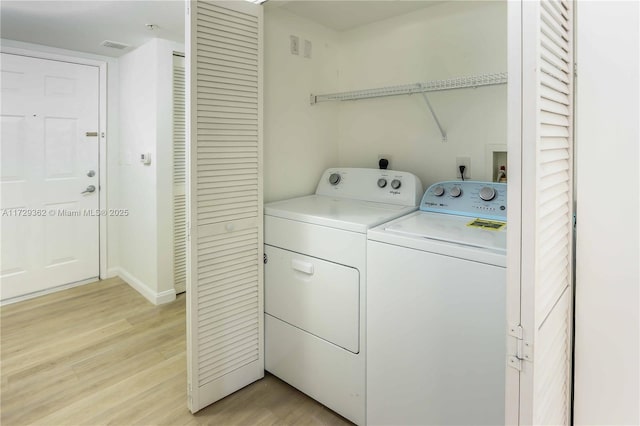 laundry area with washer and clothes dryer and light hardwood / wood-style flooring