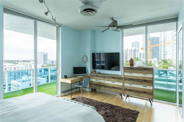 bedroom with floor to ceiling windows, access to outside, and wood-type flooring