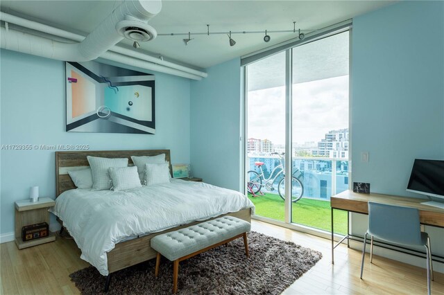 700 NE 25th St Unit 1003, Miami, FL 33137 - bedroom with expansive windows, rail lighting, access to outside, hardwood / wood-style floors, and a baseboard heating unit