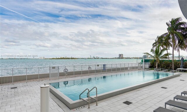 view of pool featuring a patio and a water view