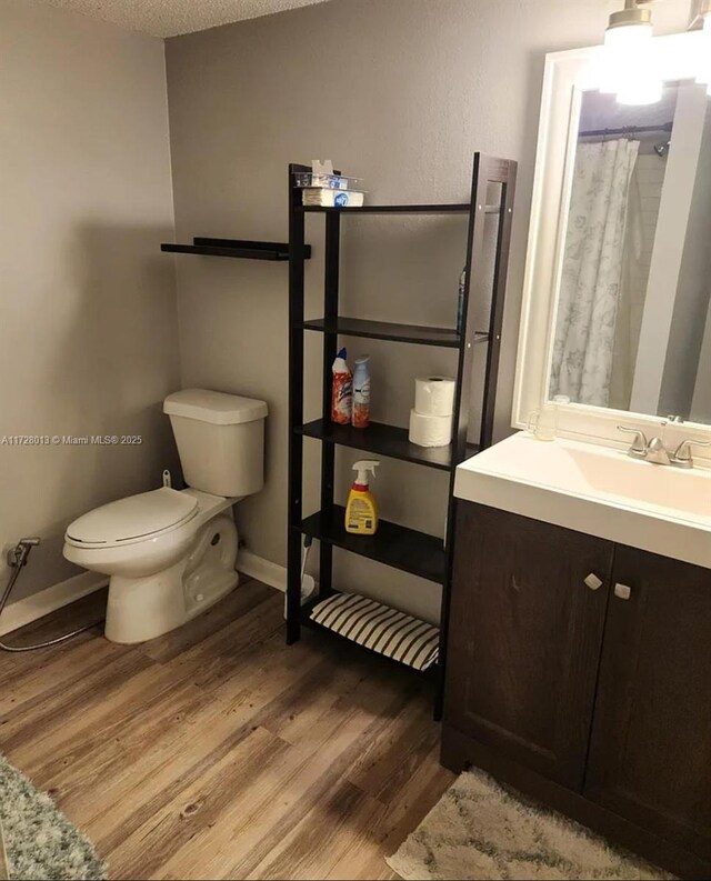 bathroom with hardwood / wood-style floors, a shower with shower curtain, vanity, a textured ceiling, and toilet