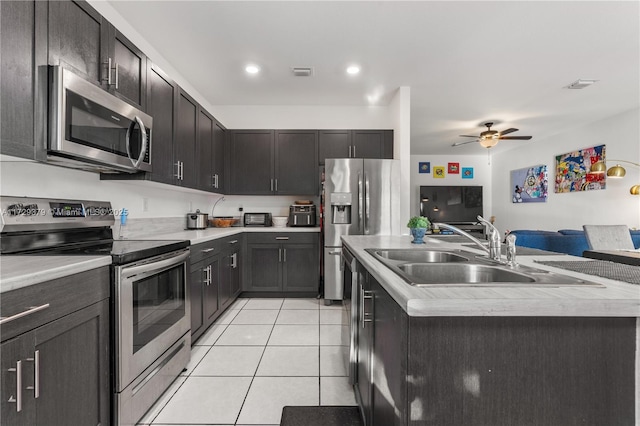 kitchen featuring stainless steel appliances, sink, a kitchen island with sink, ceiling fan, and light tile patterned floors