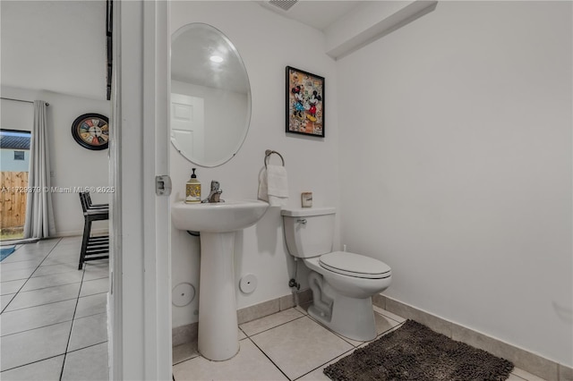 bathroom with toilet, sink, and tile patterned floors