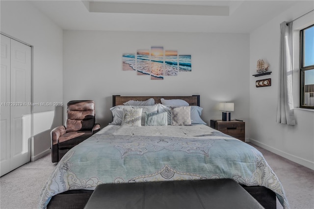 carpeted bedroom with a closet and a tray ceiling