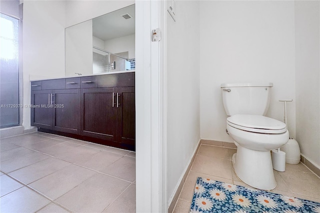 bathroom with a shower with shower door, tile patterned floors, vanity, and toilet