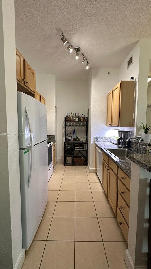 kitchen with rail lighting, white appliances, light tile patterned flooring, a textured ceiling, and sink