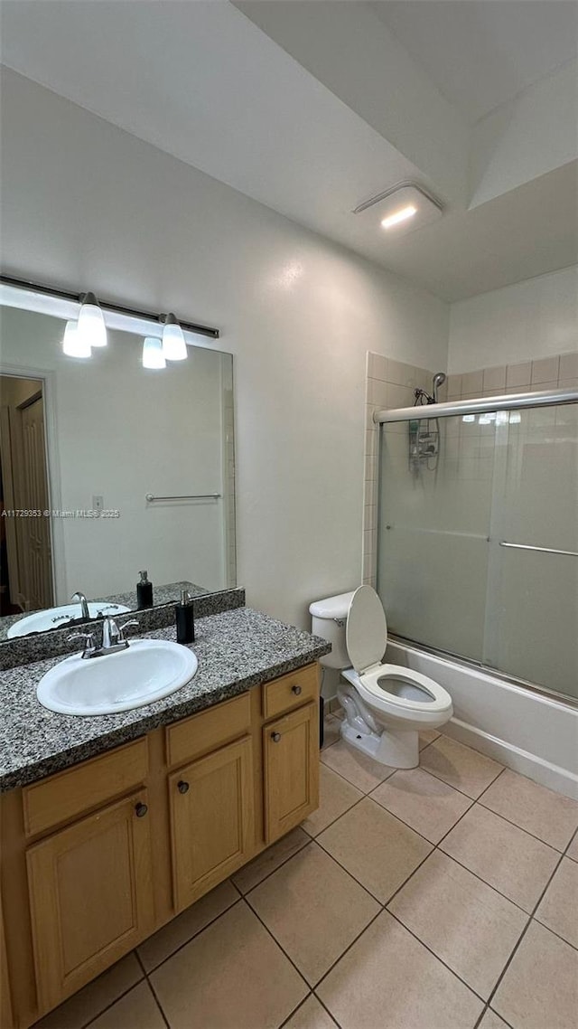 full bathroom featuring toilet, vanity, tile patterned flooring, and bath / shower combo with glass door