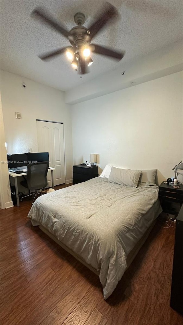 bedroom featuring ceiling fan, a textured ceiling, dark hardwood / wood-style flooring, and a closet