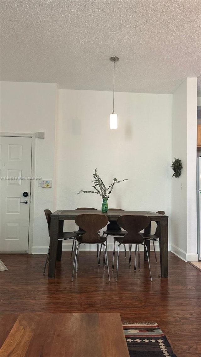 dining area with dark hardwood / wood-style flooring and a textured ceiling