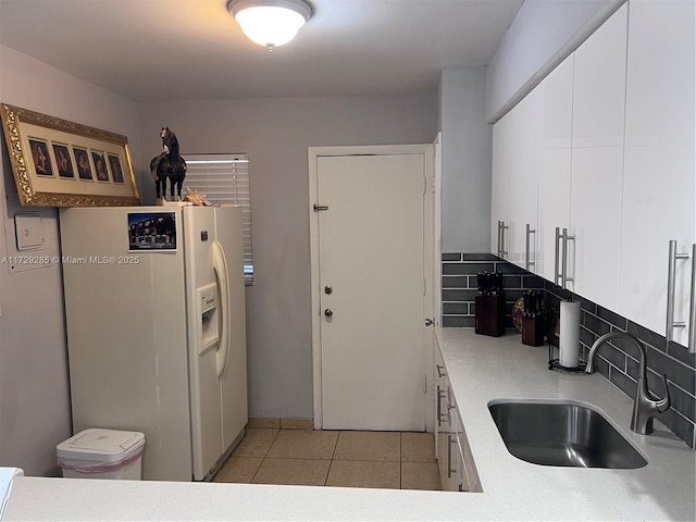 kitchen with white refrigerator with ice dispenser, light tile patterned floors, decorative backsplash, white cabinets, and sink