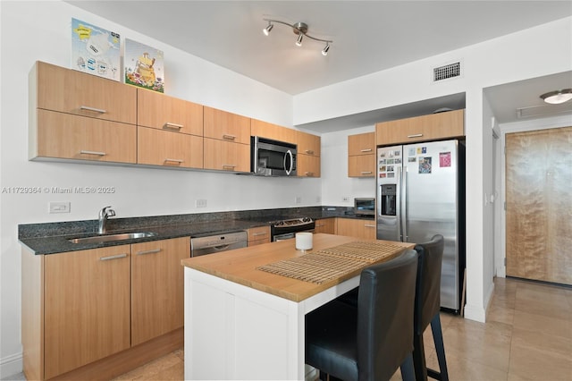 kitchen with a kitchen island, light tile patterned flooring, sink, a breakfast bar area, and stainless steel appliances