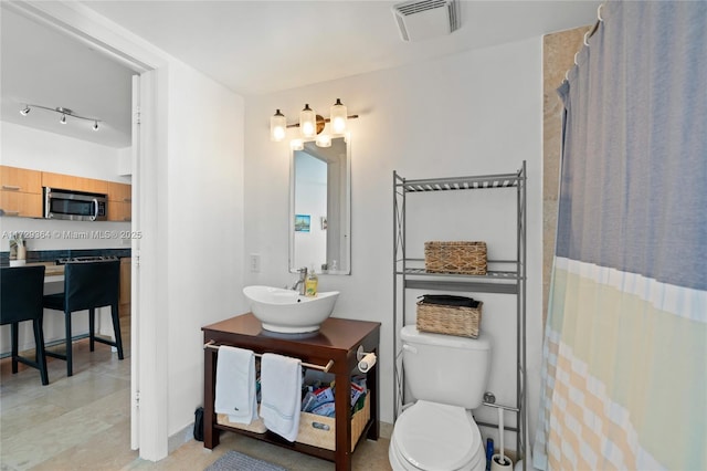 bathroom featuring toilet, vanity, and a shower with shower curtain