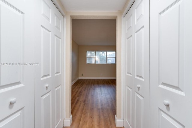 hall with light wood-style floors and baseboards