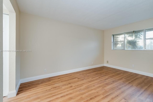 empty room with baseboards and light wood-type flooring