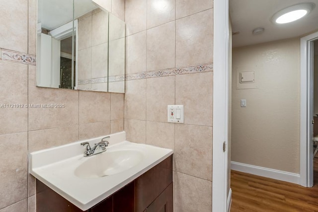 bathroom featuring baseboards, tile walls, vanity, and wood finished floors