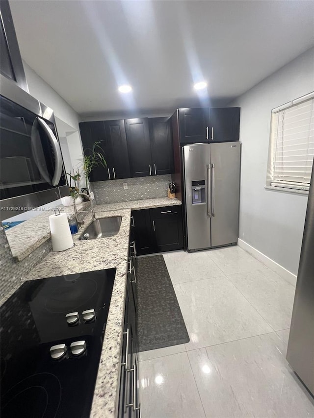 kitchen with light stone countertops, appliances with stainless steel finishes, sink, and tasteful backsplash