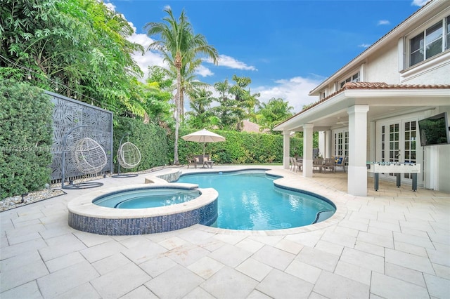 view of pool with french doors, a patio, and an in ground hot tub