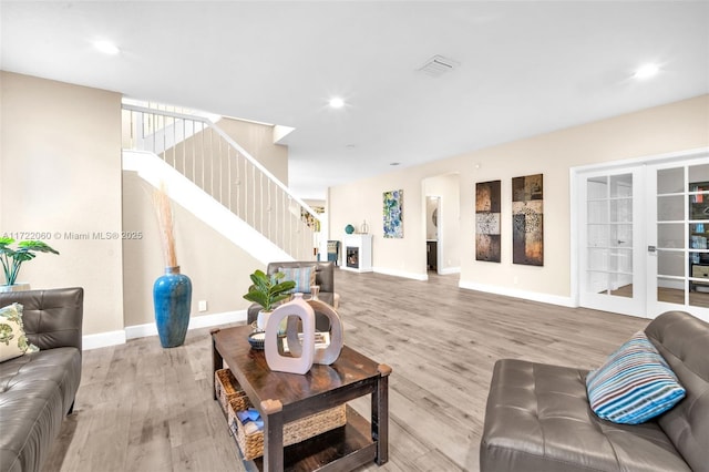 living room featuring a fireplace, light hardwood / wood-style floors, and french doors