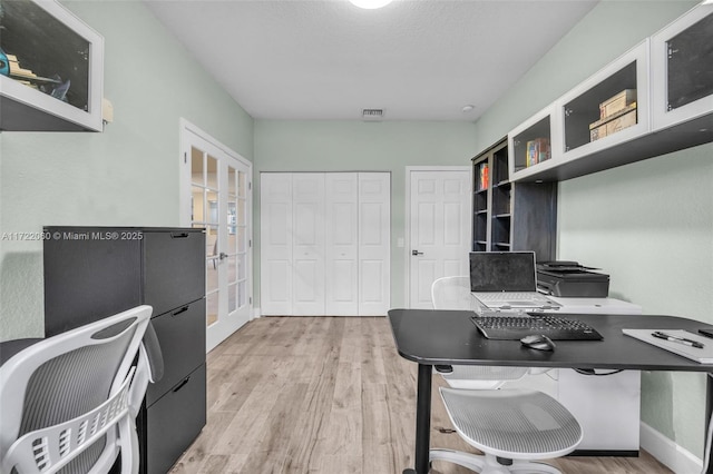 office area featuring a textured ceiling, light hardwood / wood-style floors, and french doors